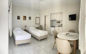 a room with two beds and a table and a kitchen at Manto Apartments in Tinos