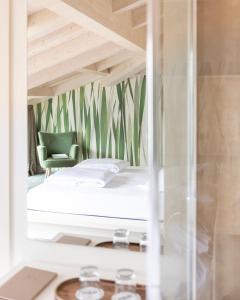 a bedroom with a bed and a green chair at Hotel Baia Azzurra - Lake Front in Nago-Torbole