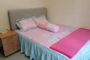 uma cama com lençóis e almofadas cor-de-rosa e uma cómoda em Aprilia Homestay Magelang em Magelang