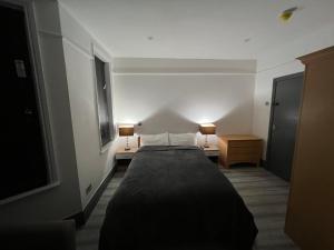 1 dormitorio con 1 cama y 2 lámparas en 2 mesas en Rooms in Modernised Victorian House en Croydon