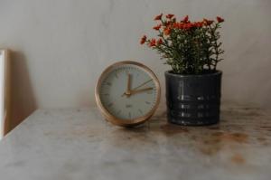 um relógio sentado numa mesa ao lado de um vaso com flores em Schloßschänke Eysölden em Thalmässing