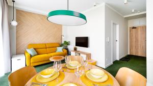a living room with a table and a yellow couch at Apartamenty Sun & Snow Wczasowa 17 in Świeradów-Zdrój