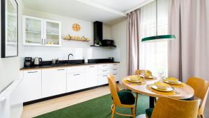 una cocina con mesa y sillas y una cocina con armarios blancos. en Apartamenty Sun & Snow Wczasowa 17 en Świeradów-Zdrój