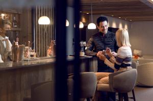 a man and a woman sitting at a bar at Antarès Méribel Resort & SPA in Les Allues