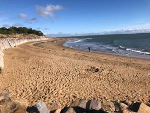 uma praia de areia com pessoas a caminhar sobre a água em Appartement bord de mer em La Tranche-sur-Mer