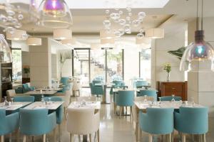 un restaurante con mesas y sillas azules y blancas en Glaros Beach Hotel en Hersonissos