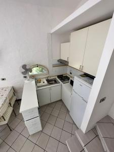 a small kitchen with white cabinets and a window at Le vasche - by the sea - nice apartment in Cavo