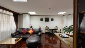 a living room with a leather couch and a table at Yellow Ribbon Hills Boutique Suites in Bangkok
