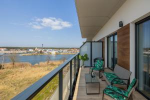 a balcony with chairs and a view of the water at Wellness & SPA Resort Dziwnów Riverfront Apartments with AC & Parking by Renters in Dziwnów