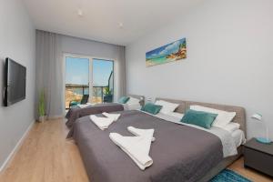 a bedroom with two beds and a flat screen tv at Wellness & SPA Resort Dziwnów Riverfront Apartments with Parking by Noclegi Renters in Dziwnów