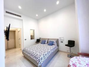 a white bedroom with a bed and a chair at SOLEIL LUXURY APARTMENT in Maiori