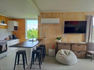 a kitchen with a counter with stools and a tv on the wall at Relax in Kenmure in Dunedin