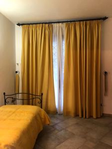 1 dormitorio con 1 cama y cortinas amarillas en B&B Villa Torri Petrose en Pontelatone