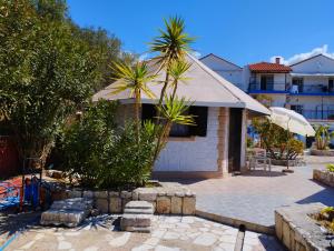 a house with a palm tree and a patio at Spasmata Village - Marios Bungalows Only Adults 2 min From The Beach in Minia
