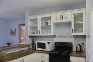 uma cozinha com armários brancos, um fogão e um micro-ondas em Launa La Crete 78 em Margate