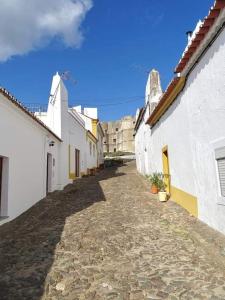 une ruelle avec des bâtiments blancs et un ciel bleu dans l'établissement Casa das Correias, à Évora Monte