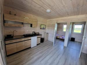 a kitchen with wooden walls and a wooden floor at Bajkowe Chatki in Rusinowo