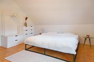 a white bedroom with a bed and a dresser at Traum Chalet mit Privatwald & Almhütte in Irdning