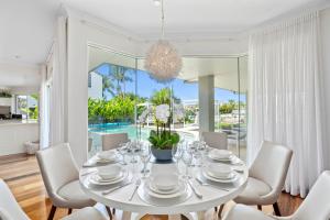 a white dining room with a table and chairs at SEACLUSION 5 bed waterfront, sleeps 12 in Gold Coast