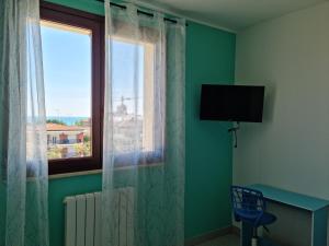 Habitación con ventana, TV y escritorio. en CASA FLAN en Porto San Giorgio