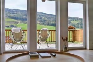 a room with two chairs in front of three windows at Traum Chalet mit Privatwald & Almhütte in Irdning