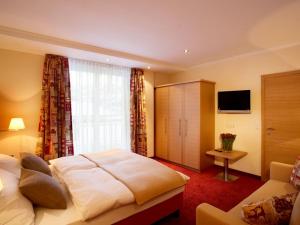 a hotel room with a bed and a television at Sonnblick Apartments und Zimmer - Nationalpark Sommercard inklusive in Hollersbach im Pinzgau