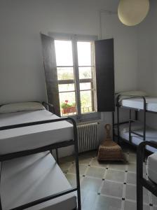 a room with three bunk beds and a window at Can Rabassa in Vallromanes