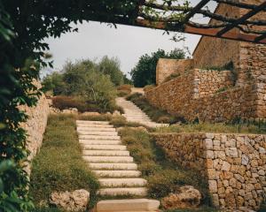 un chemin en pierre dans un jardin avec un mur en pierre dans l'établissement Es Racó d´Artà, à Artà