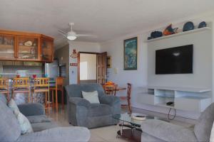 a living room with two chairs and a flat screen tv at laguna la Crete 98 in Uvongo Beach