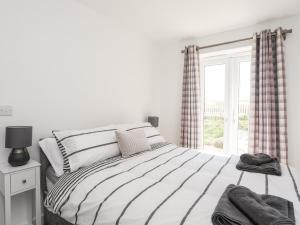 Habitación blanca con cama y ventana en 26 Awel Y Mor en Pwllheli