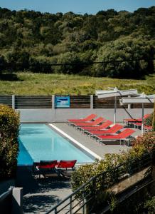 a swimming pool with red chairs and a bunch of tables at Le Golfe in Porto Pollo