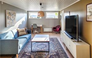 a living room with a blue couch and a tv at Stunning Home In Hvik With Wifi 