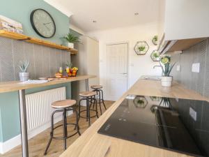 a kitchen with bar stools and a clock on the wall at The Willows in Weymouth