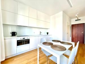 a white kitchen with a white table and chairs at Elegant Apart-800m Main Square-Parking and lift in Wrocław