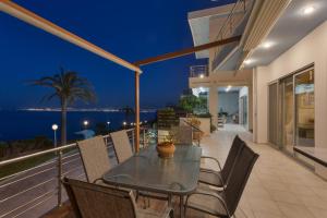 eine Terrasse mit einem Tisch und Stühlen auf dem Balkon in der Unterkunft Aegean Blue Dream Villa in Ligaria