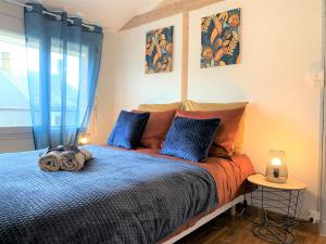 una camera da letto con un letto con cuscini blu e arancioni di Gite de la rivière avec patio et parking centre ville a Le Mans
