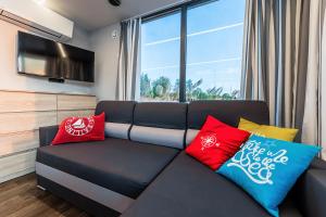 a living room with a black couch with colorful pillows at Domek na wodzie Topiko Czarter przy Hotelu Ognisty Ptak in Ogonki