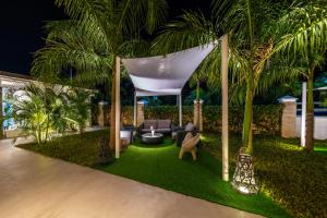 un patio trasero con cenador y palmeras por la noche en Casamia Suites, en Diani Beach
