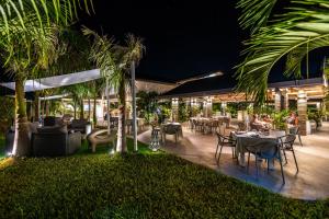 a restaurant with tables and chairs and palm trees at night at Casamia Suites in Diani Beach