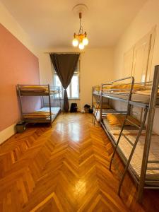 a room with three bunk beds and a wooden floor at Centrum Hostel in Pécs