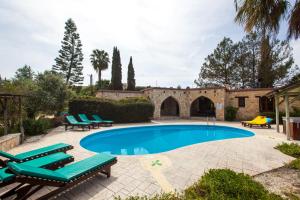 a swimming pool with lounge chairs and a house at Villa Olive Grove 3 in Paphos City