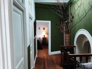 un couloir avec un mur vert et un vase avec une plante dans l'établissement Huize Carmélites, à Fumay