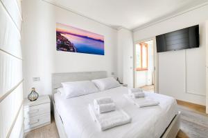 a white bedroom with a large bed and a tv at Pearl House - Sirmione Holiday - Jacuzzi Privata in Sirmione