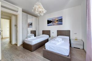 1 dormitorio con 2 camas y lámpara de araña en Pearl House - Sirmione Holiday - Jacuzzi Privata, en Sirmione