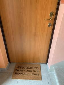 Uma porta de madeira com um sinal de boas-vindas para um cão infeliz. em Zippity Doo Dah - Menaggio Home - Como Lake em Menaggio