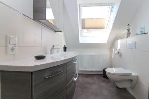 bagno con lavandino, servizi igienici e finestra di Ferienwohnungen Gatena a Norddeich