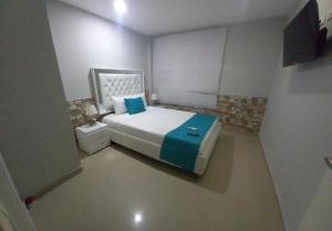 a small bedroom with a bed with a blue blanket at Bm-3 room near the sea with air conditioning and WIFI in Cartagena de Indias