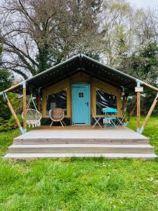 a cabin with a blue door and a wooden porch at Rendes Glamping in Balatonrendes