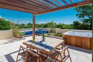 eine Terrasse mit einem Holztisch und einer Badewanne in der Unterkunft VILLA PRINCE, loft & rooftop, private pool & jaccuzi RIVIERA MAYA in Puerto Morelos