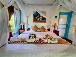ein Schlafzimmer mit einem Bett mit Handtüchern und Hüten darauf in der Unterkunft The Akah Cottage in Nusa Lembongan
